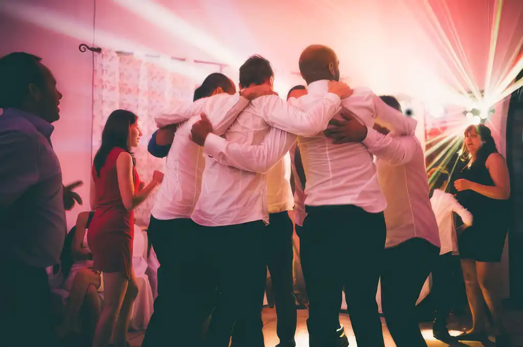 Freunde liegen sich unter buntem Partylicht in den Armen