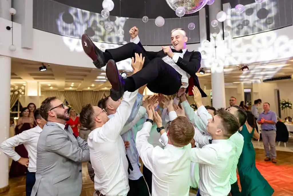 Gäste werfen einen Mann auf der Tanzfläche jubelnd in die Höhe