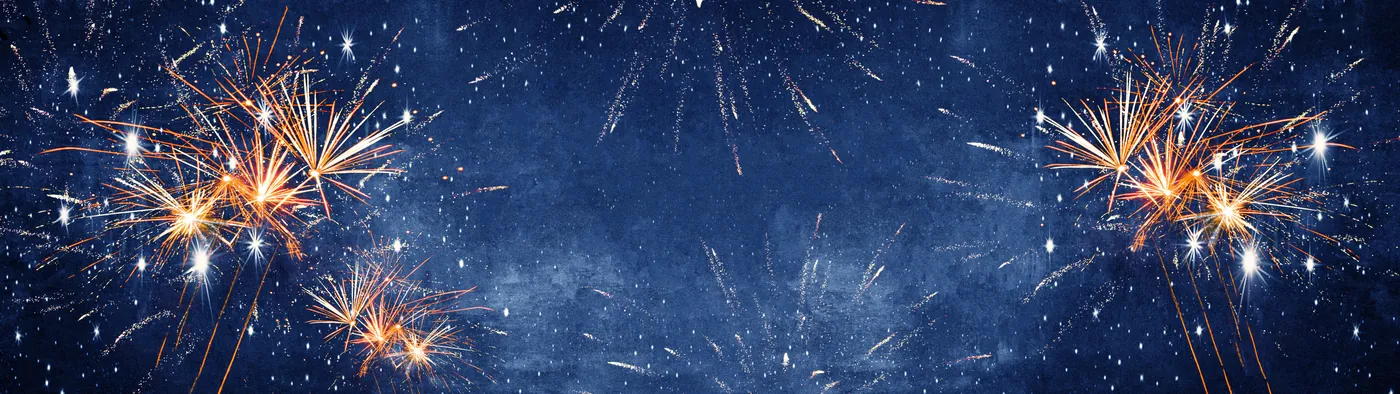 Mehrere Feuerwerksraketen explodieren am blauen Nachthimmel